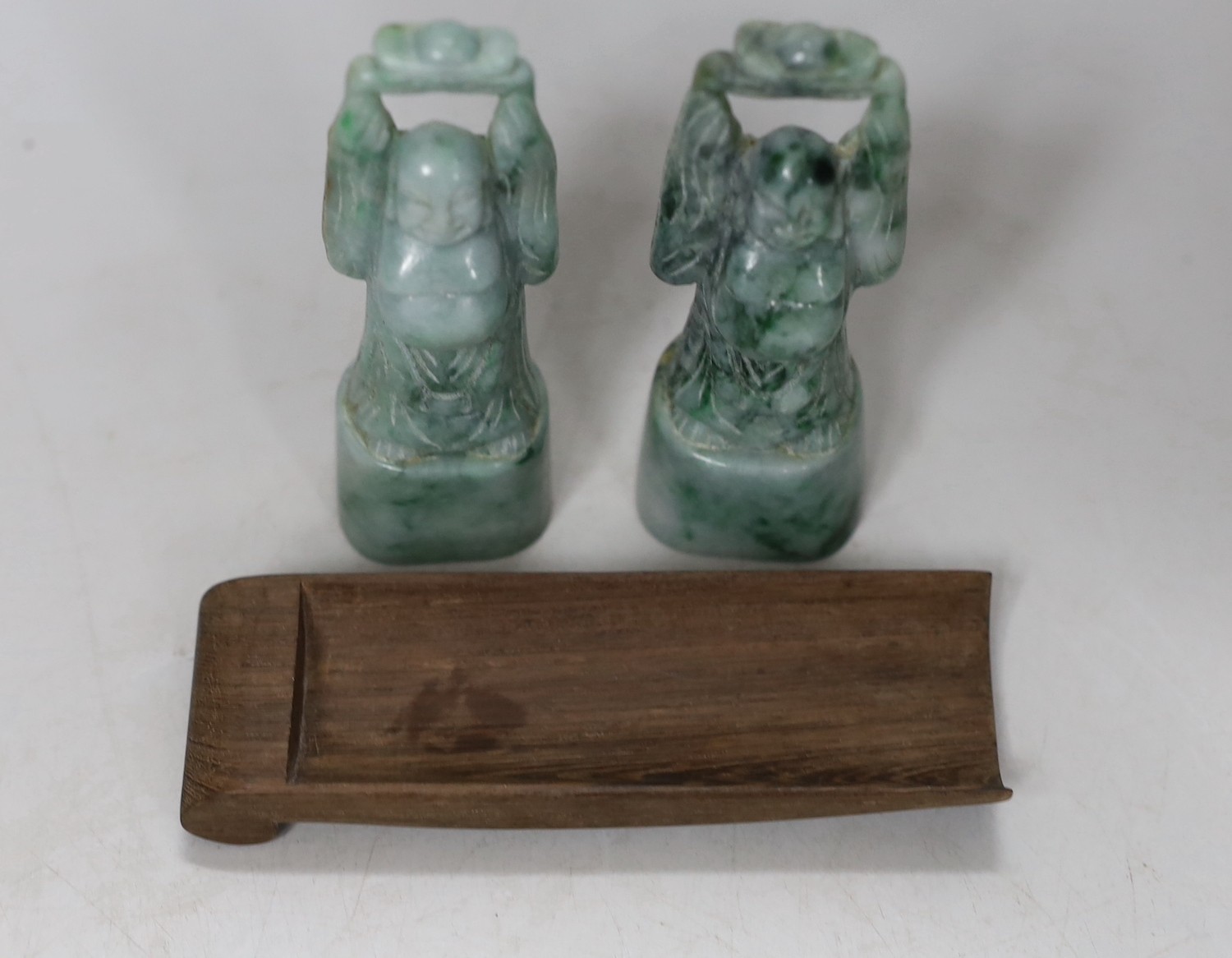 A pair of jadeite figural carvings and a gouged wood pan rest